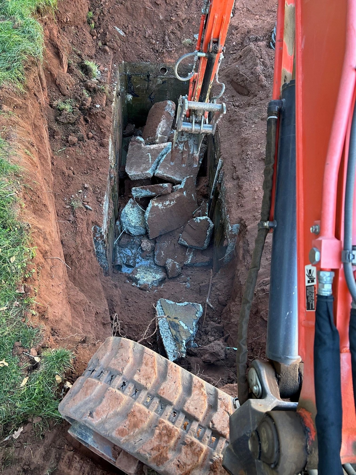 Red excavator digging trench for septic installation